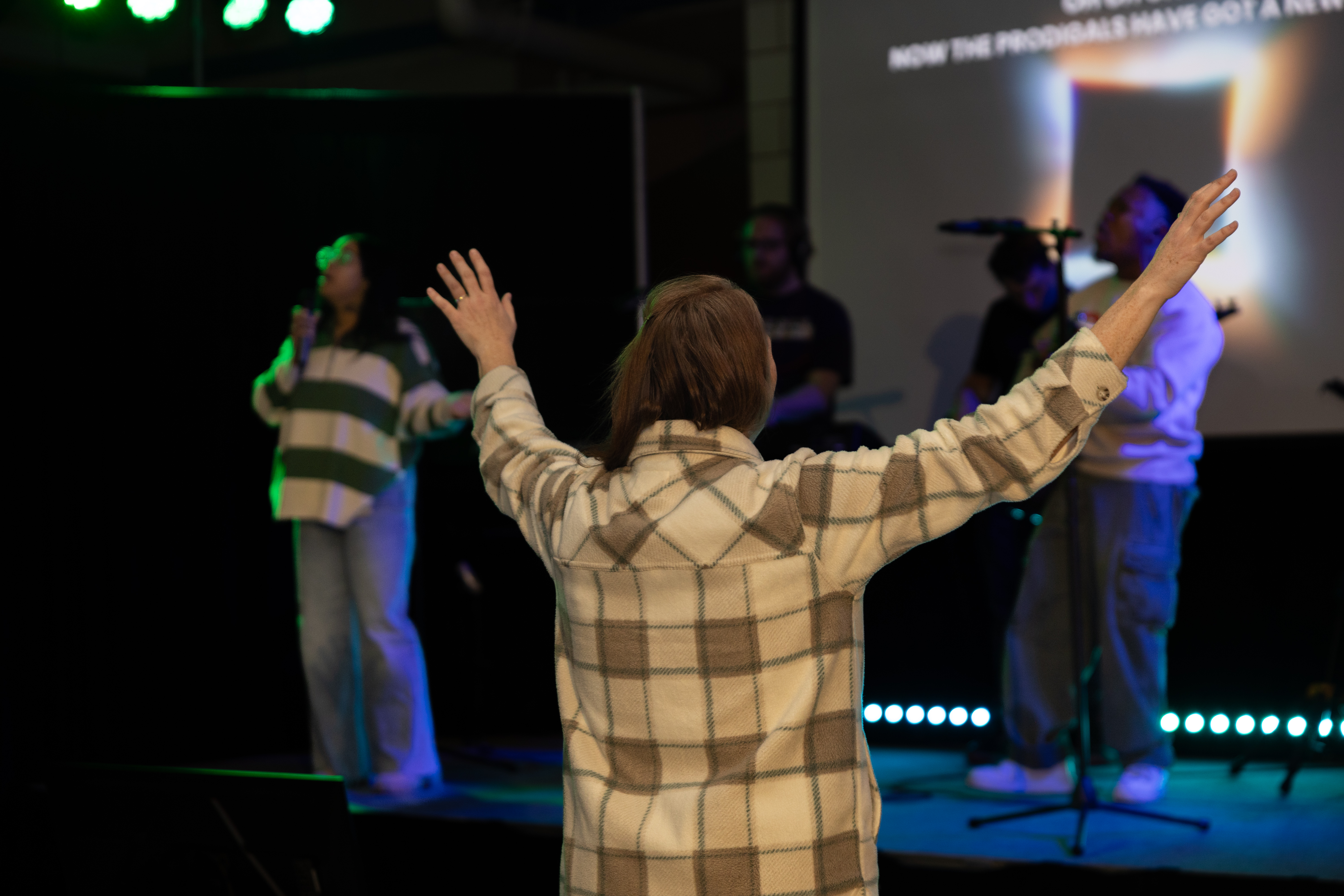 Person worshiping with raised hands during a faith gathering